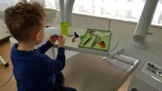 Child playing with dental instruments in a treatment room at Smilezone Zug.