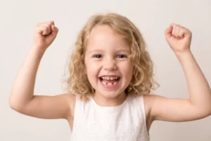 Happy girl with a gap-toothed smile, excited for her dental visit in Zug.
