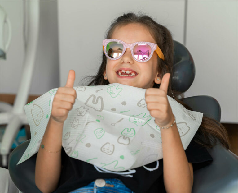 Happy child gives thumbs up after dental treatment at Smilezone Zug.