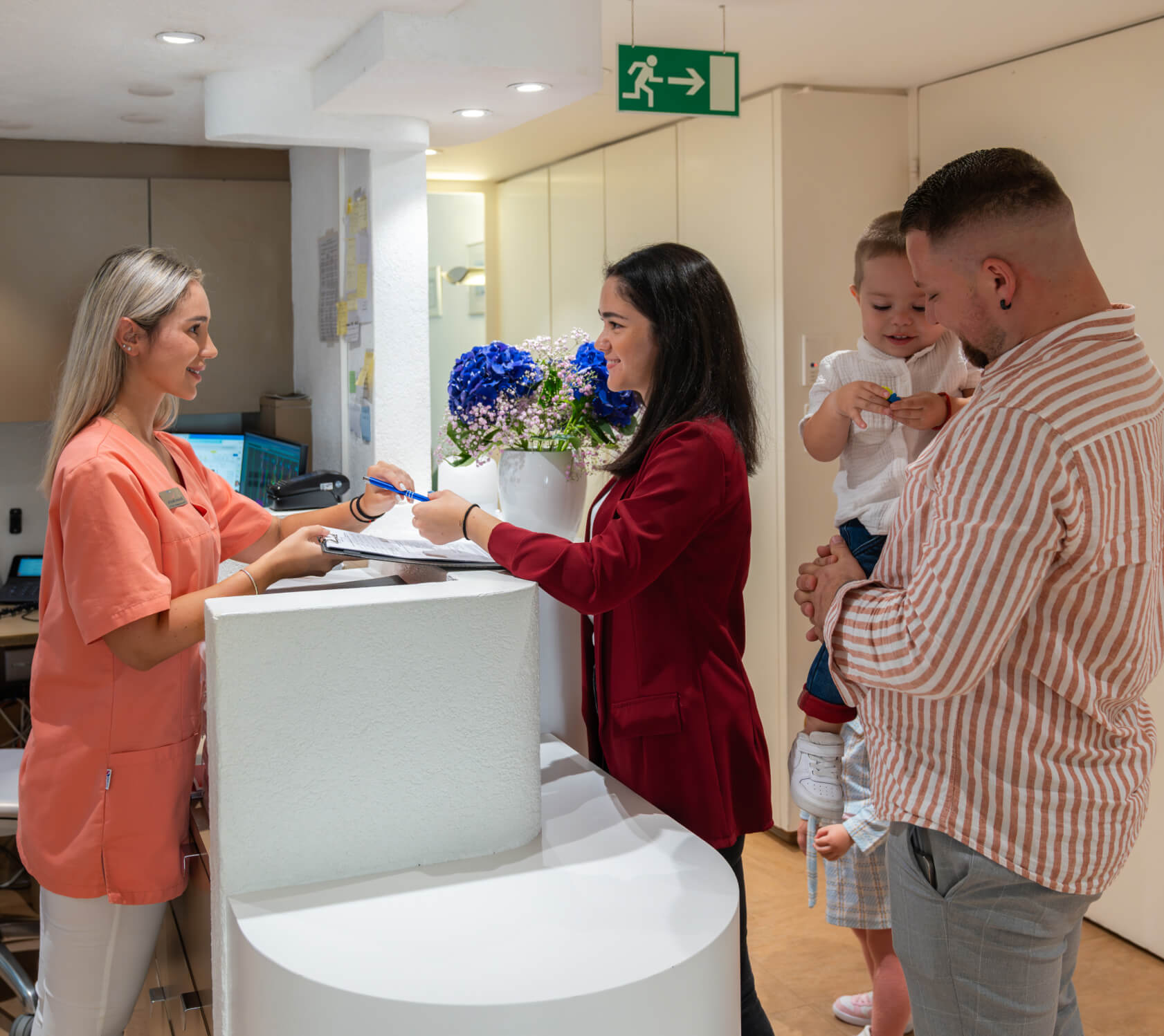 Family welcomed at Smilezone Zug reception by friendly dentist explaining treatments.