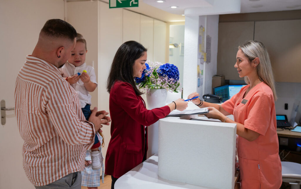 Smilezone dental practice reception area in Zug with patient and family.