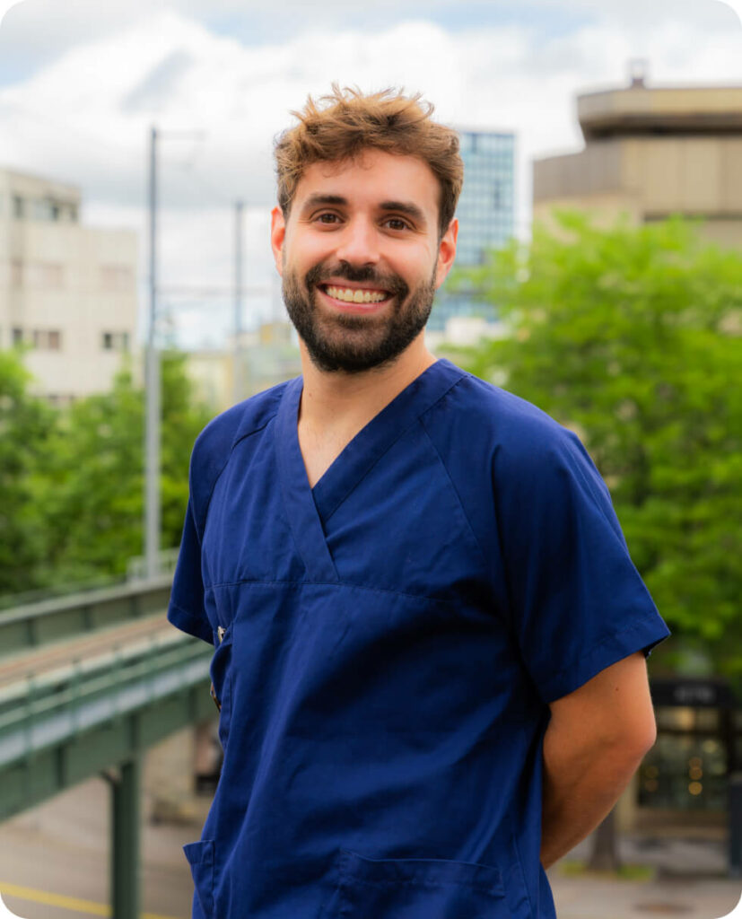 Dr. Negrini, friendly dentist at Smilezone Zug, smiles in blue scrubs.