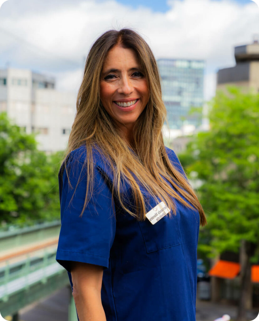 Friendly dentist Dr. Fernanda Moreira of Smilezone Zug, smiling with name tag.
