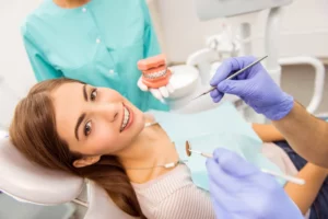 Zahnärztin zeigt Inlay und Onlay Modell während Patientin im Behandlungsstuhl lächelt in Smilezone Zug.