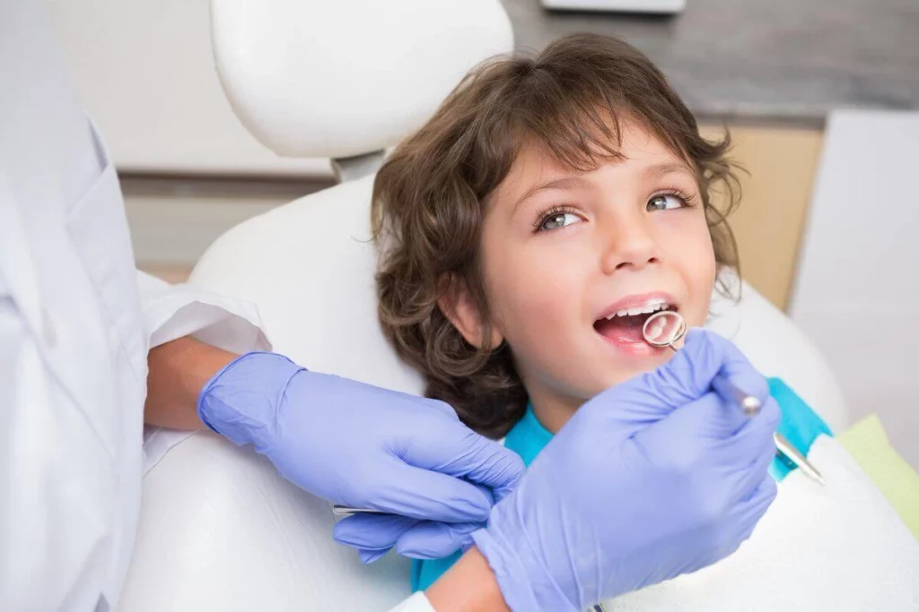 Kid dentist examining a smiling child during a pediatric dental check-up at Smilezone Zug.